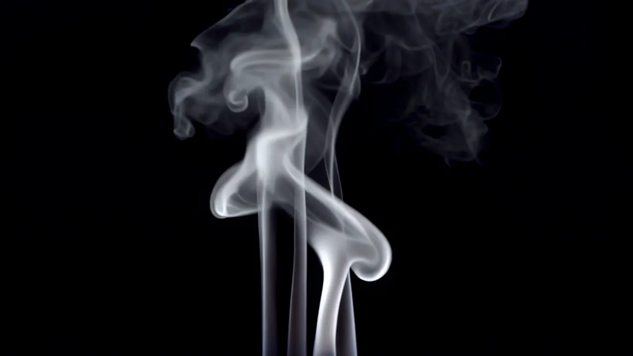 Thin Smoke Wisps Rising Against Black Background